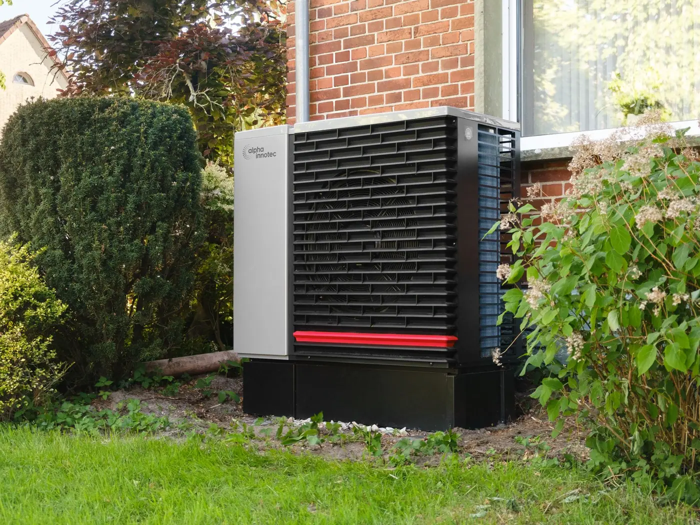 Außeneinheit einer Wärmepumpe vor einem Wohnhaus